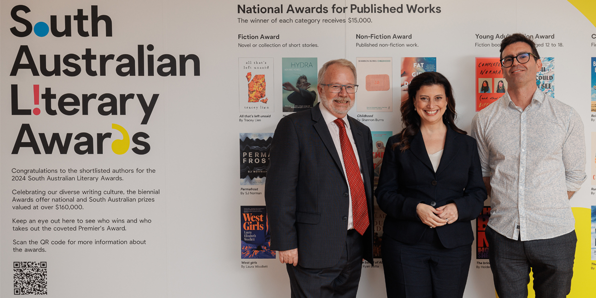 People standing in front of a wall decal promoting the SA Literary Awards