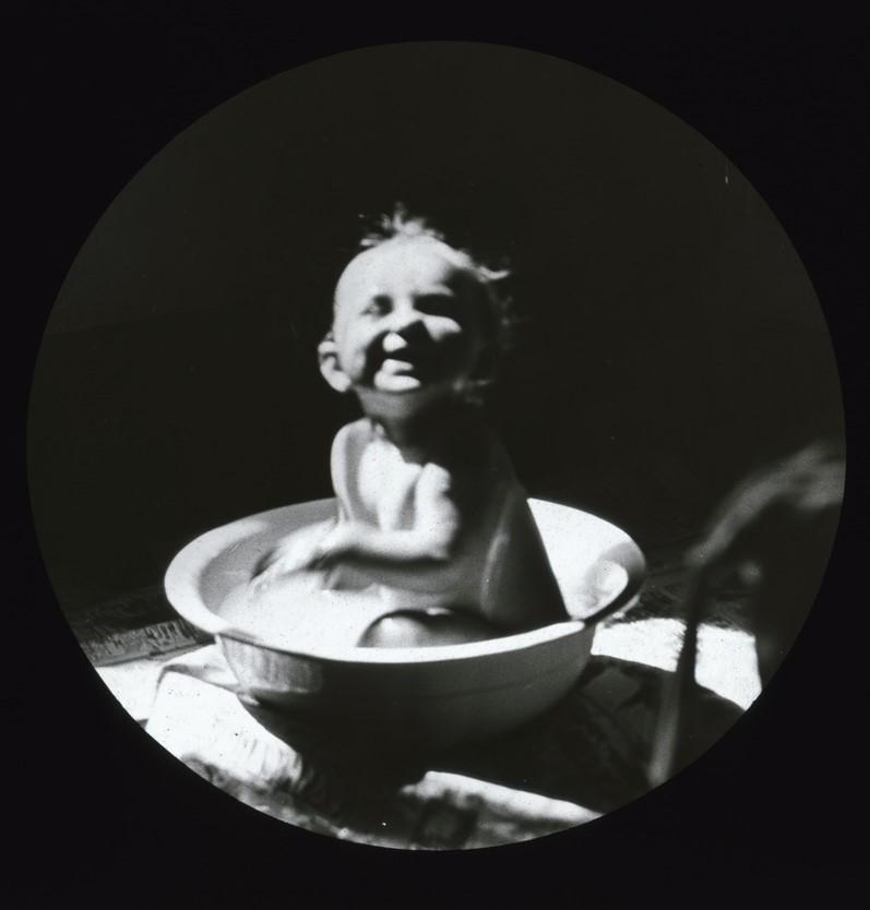 Laughing baby in washbasin, possibly Dorothy Brooker