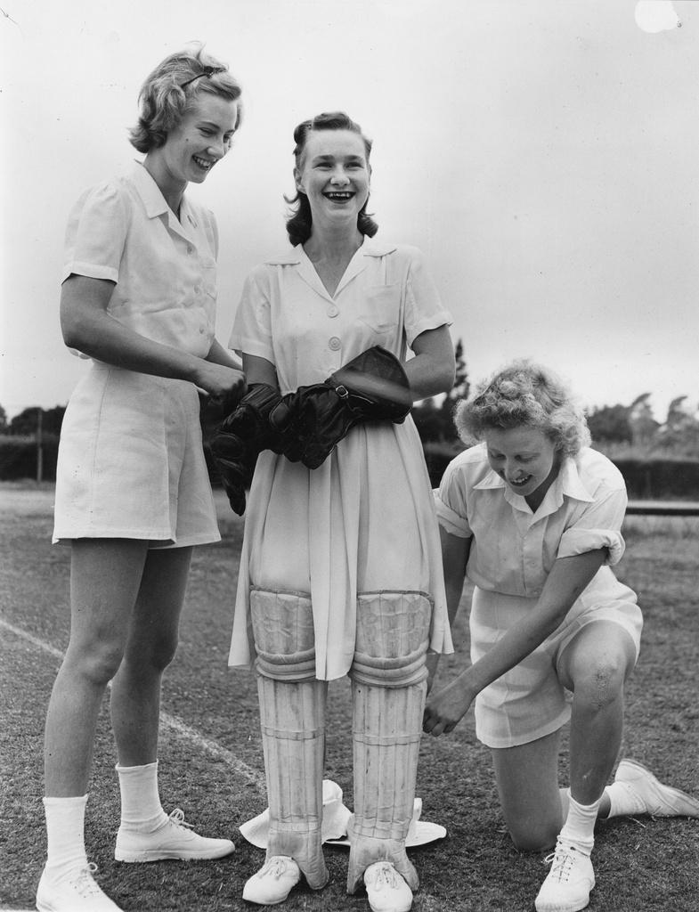 Two women cricketers assist a third to pad up, 1949. SLSA: B 7798/156