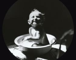 Laughing baby in washbasin, possibly Dorothy Brooker