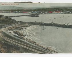 A colourised postcard showing the causeway, jetty and town buildings across the water. Photo taken from Granite Island at Port Victor in South Australia. SLSA: B 73718  