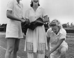 Two women cricketers assist a third to pad up, 1949. SLSA: B 7798/156