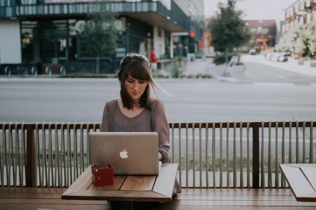 Woman sitting outside at a table with a computer