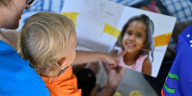 Indigenous child reading a book with an adult