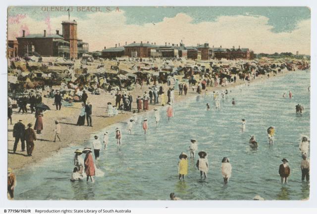 A postcard showing crowds of people at Glenelg Beach, in and out of the water, approximately 1900-1910. SLSA: B 77156/102/R      