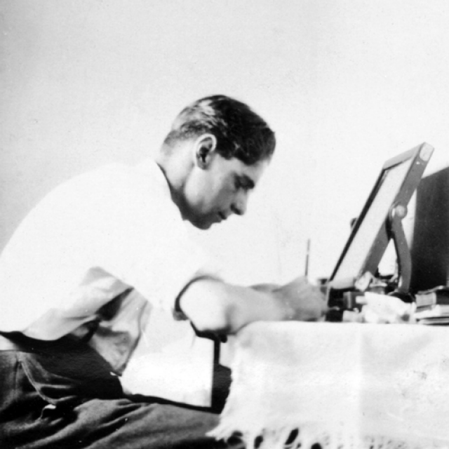 A man seated at a table writing [B 47072/49] 