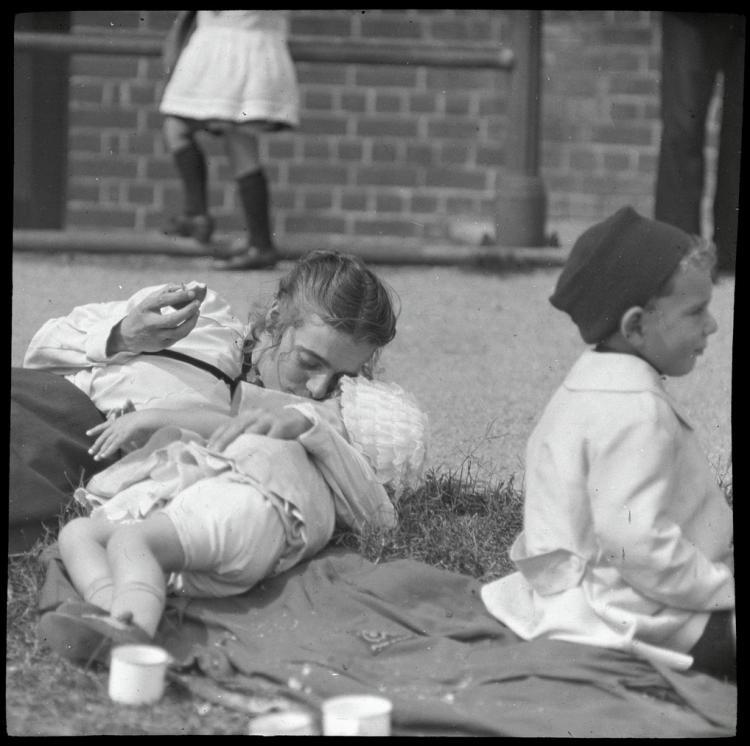 Woman kisses her baby while her son looks at other activities-Alberton Oval picnic-c 1925